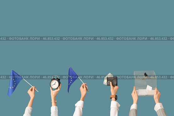 Руки держат урну для голосования, кошелек с деньгами, флаги ЕС и будильник на синем фоне. Концепция выборов. Стоковое фото, фотограф Pixel_shot / Фотобанк Лори