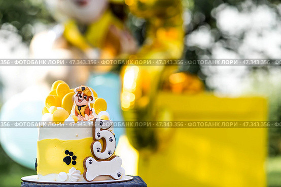 Russia, Moscow, 28 June 2024: Birthday cake at the children's birthday party "Puppy Patrol". Balloons in the background. The concept of a children's holiday in nature. Редакционное фото, фотограф Photojuli / Фотобанк Лори