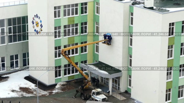 Russia, Nizhny Novgorod, Gagarin Avenue 101, School No. 34, 01.04.2021. The brigade mounts signage or advertising on the facade of the building with the use of special equipment to work at altitude. Россия, Нижний Новгород, проспект Гагарина, 101, школа № 34, 01.04.2021. Бригада монтирует вывески или рекламу на фасаде здания с использованием специального оборудования для работы на высоте. Редакционное видео, видеограф Egor Sarantstv / Фотобанк Лори