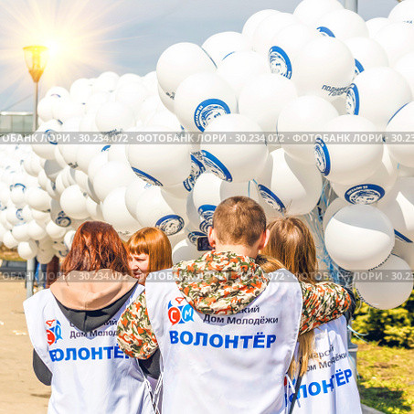 Russia, Samara, April 2016: young volunteers are preparing inflatable balls for the holiday of cosmonautics on a spring sunny day. Text in Russian: Samara youth house, volunteer, let's go. Редакционное фото, фотограф Акиньшин Владимир / Фотобанк Лори