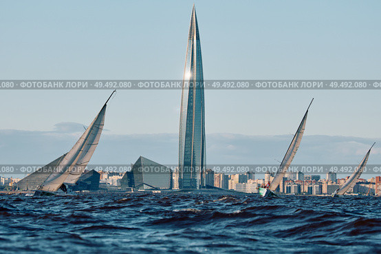 Russia, St.Petersburg, 01 June 2025: Sailing regatta in the Gulf of Finland at sunset, hot race of several yachts, teamwork, yachtsmen sitting on board the boat. Редакционное фото, фотограф Vladimir Drozdin / Фотобанк Лори
