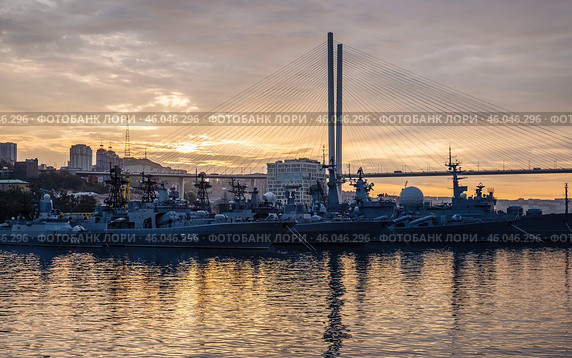 Russian navy warships are anchored in vladivostok harbor at sunset under the zolotoy rog bridge, creating a powerful image of maritime defense. Стоковое фото, фотограф Mikhail Davidovich / Фотобанк Лори