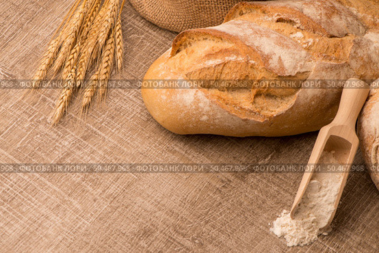 Rustic bread and wheat on an old vintage planked wood table. Стоковое фото, агентство Ingram Publishing / Фотобанк Лори