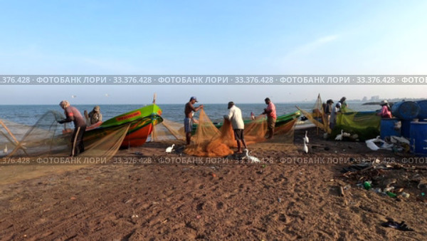 Рыбаки на берегу Индийского океана разбирают сети после рыбалки. Негомбо, Шри-Ланка (2020 год). Редакционное видео, видеограф Виктор Карасев / Фотобанк Лори