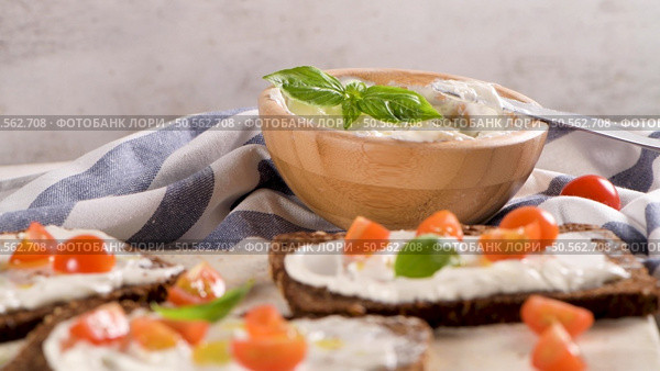 Rye bread bruschetta with cream cheese, olive oil and basil dip, cherry tomatoes, fresh basil leaves on wooden board. Стоковое фото, агентство Ingram Publishing / Фотобанк Лори