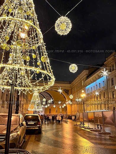 SAINT PETERSBURG, RUSSIA-December 25, 2023: People walking along Bolshaya Morskaya Street decorated with garlands and Christmas trees near arch of General Staff Building in X-Mas and New Year holidays. Редакционное фото, фотограф Виктория Катьянова / Фотобанк Лори