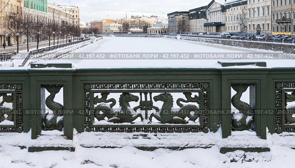 SAINT PETERSBURG, RUSSIA - January 17, 2024: View of the snow-covered Fontanka River from the famous Anichkov Bridge, decorated with a cast iron fence with seahorses on a sunny winter day. Редакционное фото, фотограф Виктория Катьянова / Фотобанк Лори