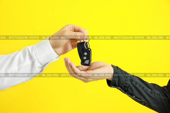 Salesman giving car keys to woman on color background. Стоковое фото, фотограф Pixel_shot / Фотобанк Лори