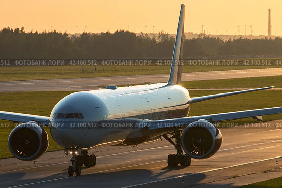 Самолет Boeing 777 авиакомпании "Россия" (Rossiya Airlines) на рулежной дорожке аэропорта Пулково во время красивого заката (2016 год). Редакционное фото, фотограф Сергей Крамарев / Фотобанк Лори