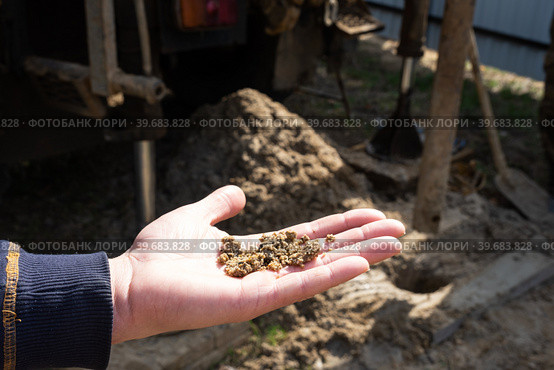 Sandy rocky soil of the aquifer from the well are drilling artesian well for water in ground. Insertion of metal casing pipe into ground, installation of individual drinking supply, June 28, 2022, Russia, Стоковое фото, фотограф Ольга Симонова / Фотобанк Лори
