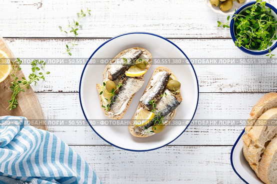 Sardines sandwiches on a white wooden background. Mediterranean food. Top view. Стоковое фото, агентство Ingram Publishing / Фотобанк Лори