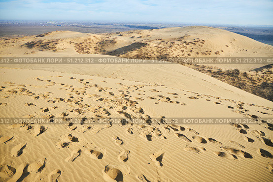 Sarykum dune, the largest sand dune in Europe.. A desert scene with a large mound of sand. The sand is dry and the sun is shining brightly. Стоковое фото, фотограф Наталия Кирсанова / Фотобанк Лори
