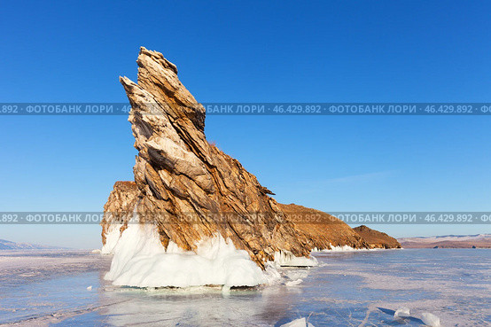 Scenic winter landscape of frozen Baikal Lake. View of Dragon Cape on edge of Ogoy Island - natural landmark and popular place of tourists against background of blue sky in sunny day. Natural background. Стоковое фото, фотограф Виктория Катьянова / Фотобанк Лори