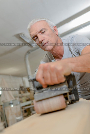Senior carpenter using a belt sander. Стоковое фото, агентство Ingram Publishing / Фотобанк Лори
