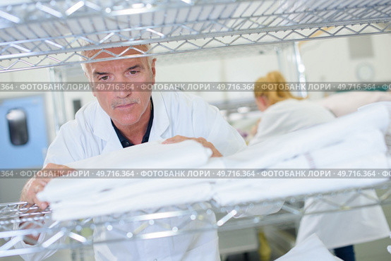 Senior man stacking clean laundry on shelf. Стоковое фото, агентство Ingram Publishing / Фотобанк Лори