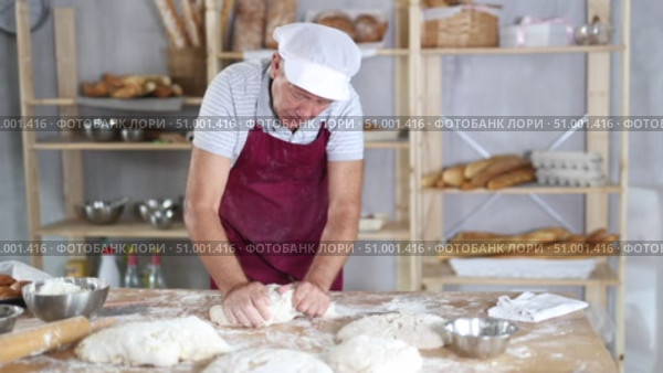 Senior man works in bakery as baker, kneads dough, works with flour. Стоковое видео, видеограф Яков Филимонов / Фотобанк Лори