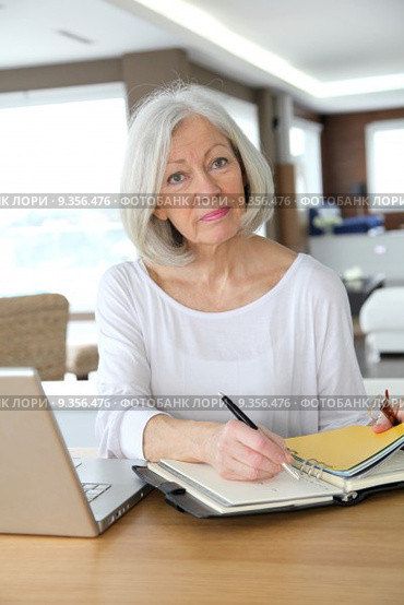 Senior woman at home writing on agenda. Стоковое фото, фотограф Fabrice Michaudeau / PantherMedia / Фотобанк Лори