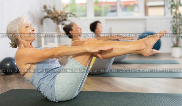 Senior woman performs boat asana - Paripurna navasana. Стоковое фото, фотограф Яков Филимонов / Фотобанк Лори