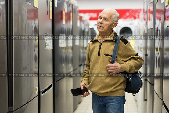 Senor man pensioner buying fridge in showroom of electrical appliance store. Стоковое фото, фотограф Татьяна Яцевич / Фотобанк Лори