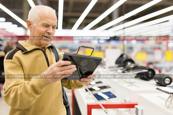 senor man pensioner buying modern tablet digital in showroom of digital electronic goods store. Стоковое фото, фотограф Татьяна Яцевич / Фотобанк Лори