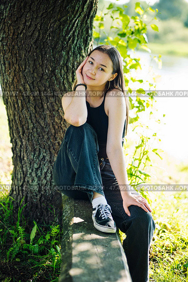 Serene student enjoying a tranquil moment in nature, surrounded by lush greenery and embracing the peacefulness of the outdoors. Стоковое фото, фотограф Mikhail Davidovich / Фотобанк Лори
