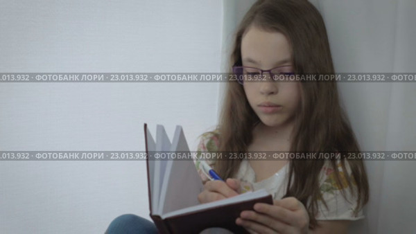Серьезные маленькая девочка в очках записывает что-то в своем дневнике. Стоковое видео, видеограф Юлия Машкова / Фотобанк Лори