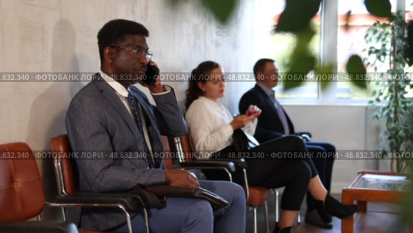 Serious-minded African male candidate siting on chair and waiting for job interview in hallway. Стоковое видео, видеограф Яков Филимонов / Фотобанк Лори