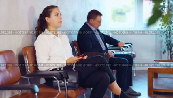 Serious-minded female candidate siting on chair and waiting for job interview in hallway. Стоковое видео, видеограф Яков Филимонов / Фотобанк Лори