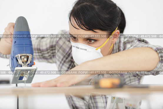 serious woman with mask cutting wood. Стоковое фото, агентство Ingram Publishing / Фотобанк Лори