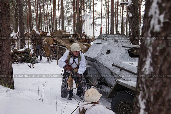 Sestroretsk, Russia - February 19, 2023: Soldiers in winter gear engage in a tactical exercise amidst snow-covered trees and military vehicles, depicting the grit of Second World War battles. Редакционное фото, фотограф Aleksandr Golubev / Фотобанк Лори
