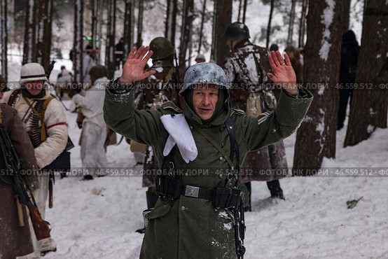 Sestroretsk, Russia - February 19, 2023: Soldiers reenacting the winter battle of the Second World War raise their hands in surrender amid a snowy forest setting, capturing the intensity of warfare. Редакционное фото, фотограф Aleksandr Golubev / Фотобанк Лори