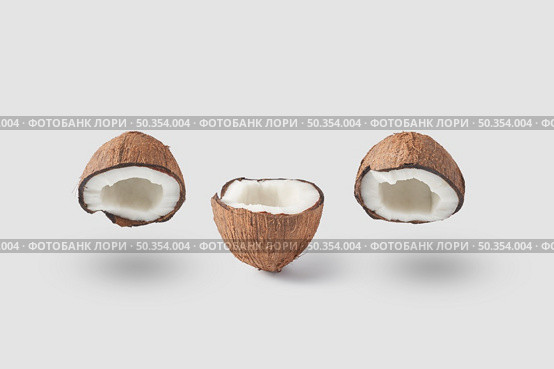 Set of natural coconut in halves with fresh ripe pulp and dry brown shell composed in row on white background casting shadows. Cracked halves of raw fresh coconut. Стоковое фото, агентство Ingram Publishing / Фотобанк Лори