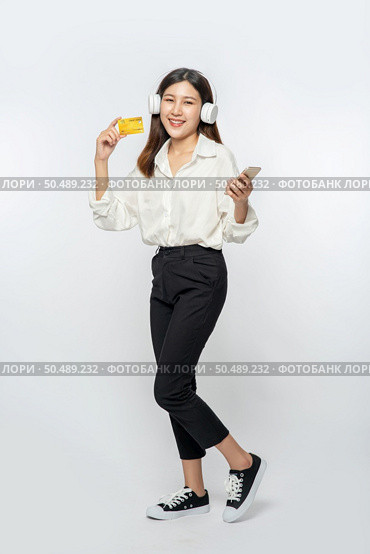 She was dressed in a white shirt and black pants to go shopping and hold a credit card and smartphone. Стоковое фото, агентство Ingram Publishing / Фотобанк Лори