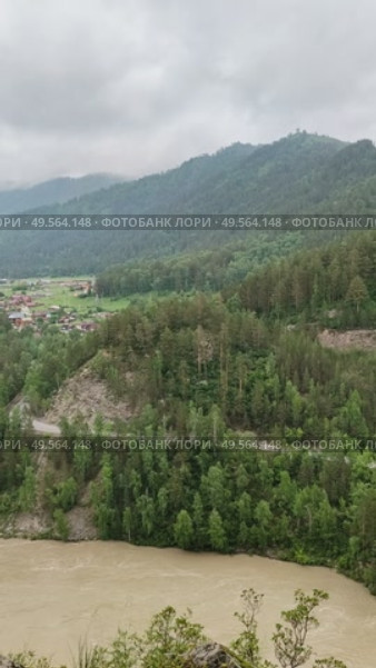 Шикарный вид на разлившуюся реку мощно бегущую в Катунь с горы в деревне мастеров и художников Аскат в горном Алтае на фоне гор и зеленых холмов с тяжелыми, свинцовыми облаками на небе. Стоковое видео, видеограф Светлана Русских / Фотобанк Лори