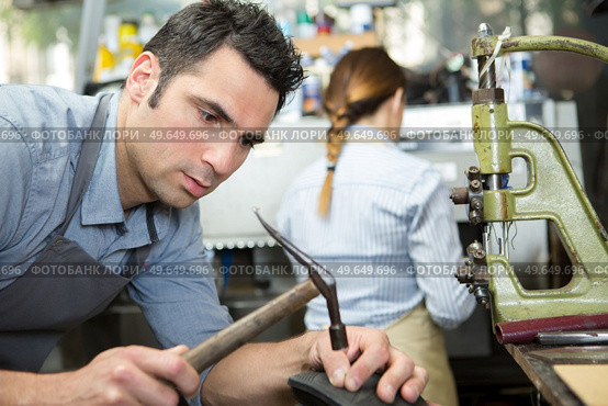 shoemaker hammering on a shoe in workshop. Стоковое фото, агентство Ingram Publishing / Фотобанк Лори