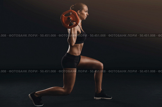 Shot of a beautiful young woman in a workout gear lifting weights. Стоковое фото, агентство Ingram Publishing / Фотобанк Лори