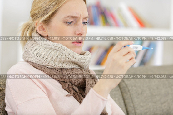 sick woman with fever checking her temperature with a thermometer. Стоковое фото, агентство Ingram Publishing / Фотобанк Лори