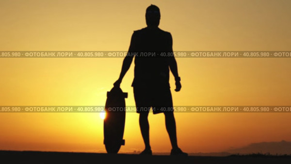 Silhouette of a man standing on sunset holding a longboard. Стоковое видео, видеограф Константин Шишкин / Фотобанк Лори