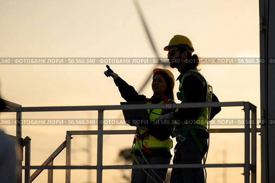 Silhouette of engineer and worker discussing with wind turbine generator at sunset. Стоковое фото, агентство Ingram Publishing / Фотобанк Лори