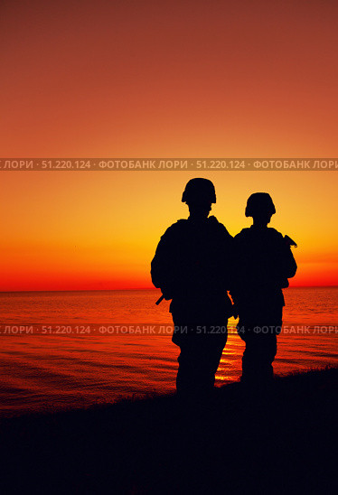 Silhouette of two soldiers patrolling a coastline at sunset. Oleg Zabielin / Stocktrek Images/TASS. Стоковое фото, агентство ТАСС / Фотобанк Лори