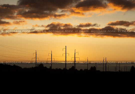 Silhouettes of power poles against background of an orange sunset sky and floating clouds (2023 год). Стоковое фото, фотограф Попова Ольга / Фотобанк Лори