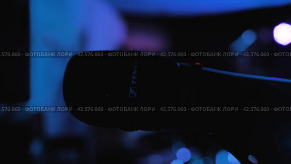 Силуэт микрофона Sennheiser на сцене. Разноцветные вспышки света на заднем плане. Концерт в ночном клубе. Краснодар, Россия, 26 августа 2023 года. Редакционное видео, видеограф Воловодов Владимир / Фотобанк Лори