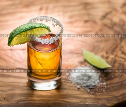 Single shot of tequila served with lime and salt on the wooden background. Стоковое фото, агентство Ingram Publishing / Фотобанк Лори