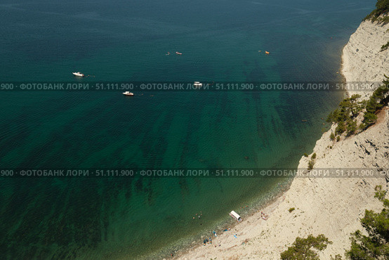 Скальный берег и прозрачная бирюзовая вода Черного моря с катерами и отдыхающими на пляже Голубая Бездна. Стоковое фото, фотограф Николай Васильев / Фотобанк Лори