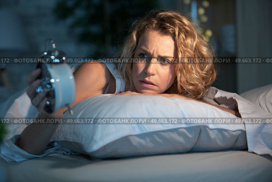 sleepless woman lying in bed looking at her clock. Стоковое фото, агентство Ingram Publishing / Фотобанк Лори