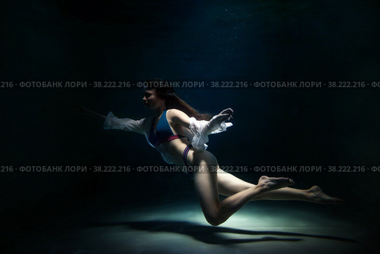 Slender pretty young woman brunette in bathing suit and white blouse in dark pond, illuminated by moonlight. Elegant female underwater. Concept of beauty, tenderness and striving for ideal. Copy space. Стоковое фото, фотограф Aleksandr Golubev / Фотобанк Лори