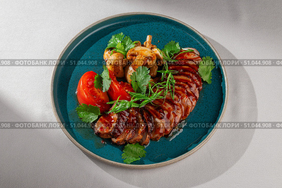 Sliced glazed duck breast served with grilled mushrooms, fresh tomatoes, cilantro and green onions on a rustic blue ceramic plate, Korean fusion presentation. Стоковое фото, фотограф Aleksandr Gavrilychev / Фотобанк Лори