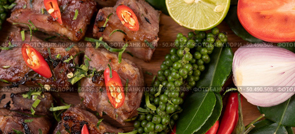 Sliced ??pork steak topped with white sesame and fresh pepper seeds along with tomatoes, lemons, chili and lettuce. Стоковое фото, агентство Ingram Publishing / Фотобанк Лори