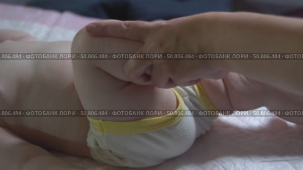 Slow-motion video of bicycle leg massage for an infant under one year to improve hip and knee joint mobility. Pediatric physiotherapy technique. Стоковое видео, видеограф Татьяна Степанищева / Фотобанк Лори