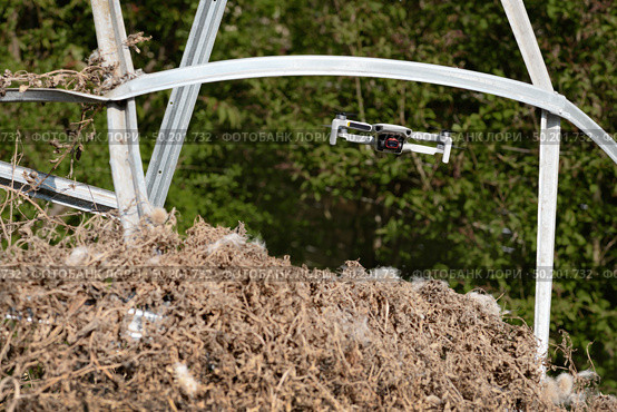 Small Flying Quadcopter Drone in flight mode with camera pointed at viewer outdoor destroyed rebar frame. Стоковое фото, фотограф Camptoloma / Фотобанк Лори